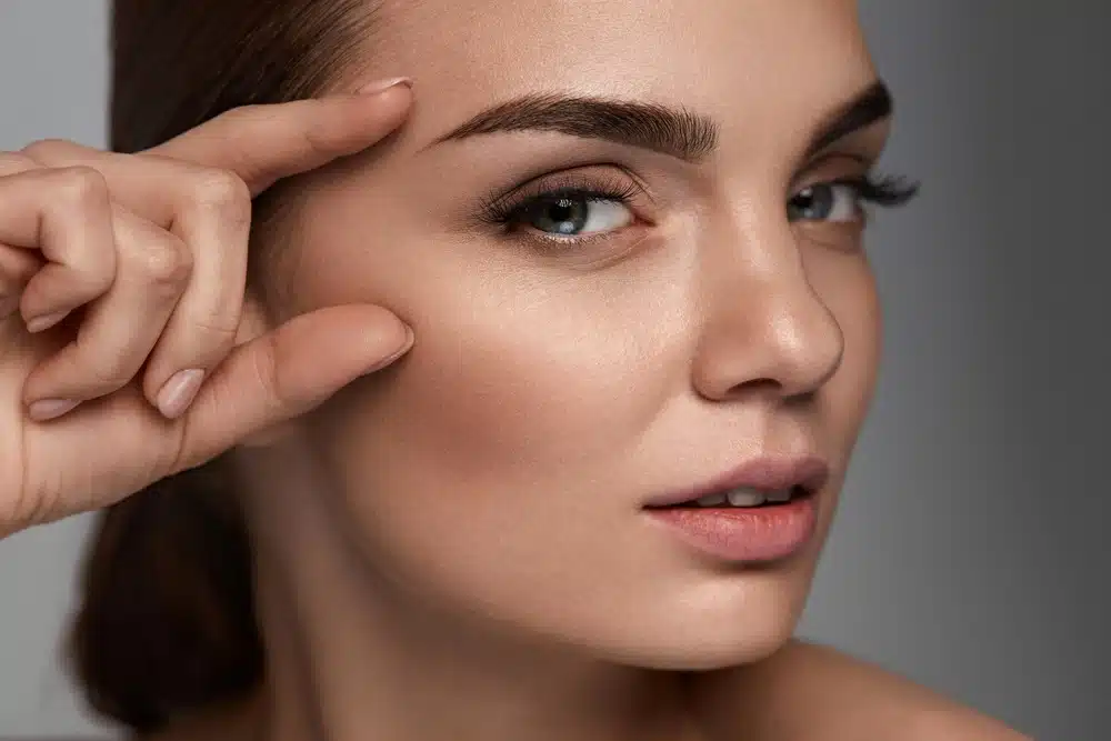 Woman holding her brow in relation to microblading