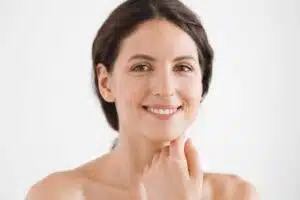Young woman with firm skin and subtle smile, illustrating benefits of a mini facelift for early aging signs.