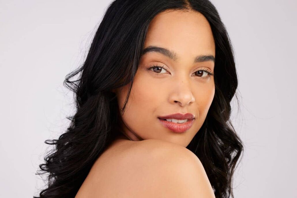 Confident woman with glowing skin and soft waves, representing ideal mini facelift results for various age groups