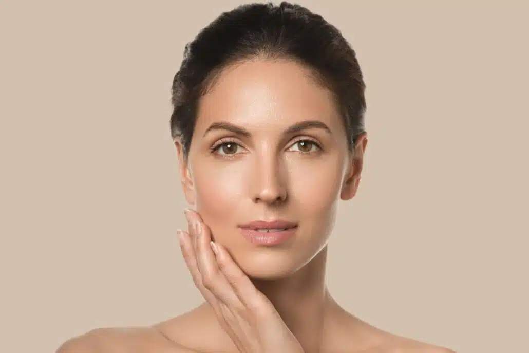 Woman with smooth skin gently touching face, showing typical Jeuveau results after consistent wrinkle treatment