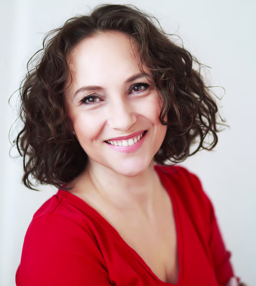 Smiling woman with curly hair and glowing skin, reflecting personalized mini facelift results with facial harmony.