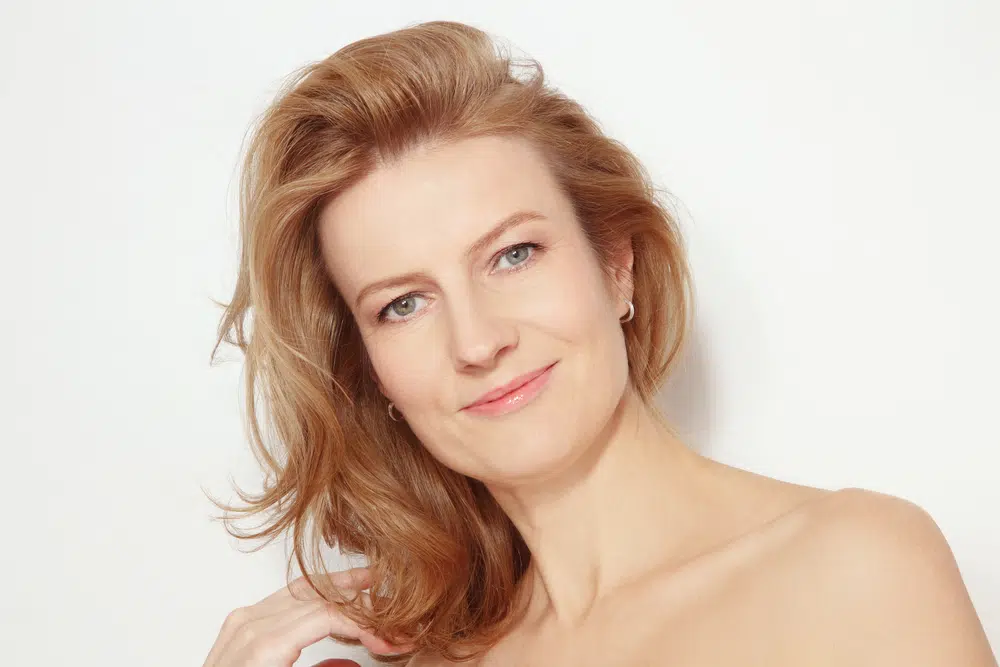 A close-up portrait of a woman with light brown hair and a gentle smile, showcasing a youthful and natural appearance, perfect for a discussion about Botox and dermal fillers for facial rejuvenation.