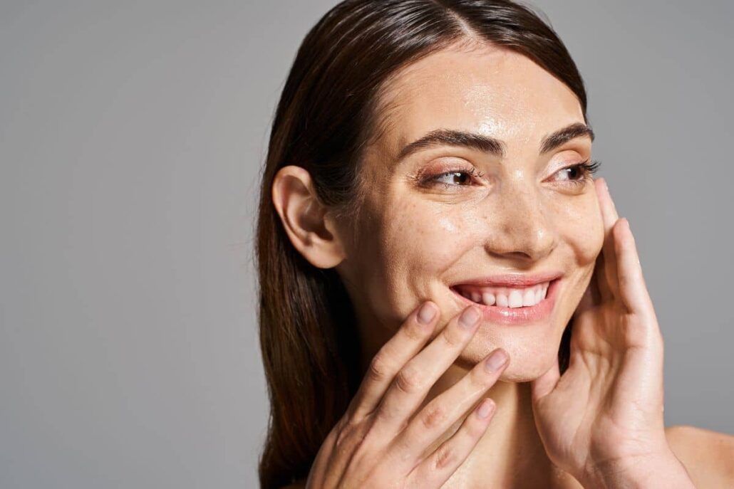Woman smiling and touching her glowing skin, illustrating the smoothing effects of Botox on facial wrinkles