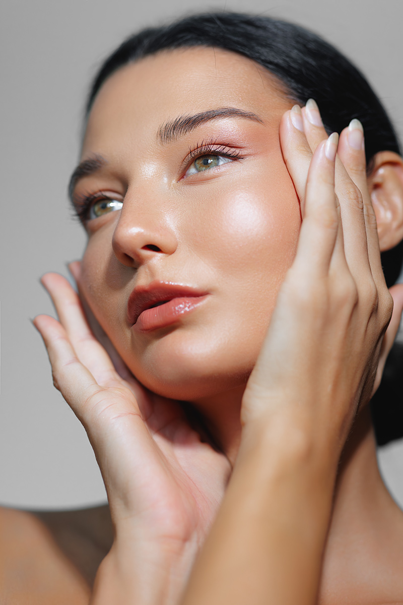 Woman touching face highlighting smooth skin and refined nose after rhinoplasty procedure in Princeton New Jersey