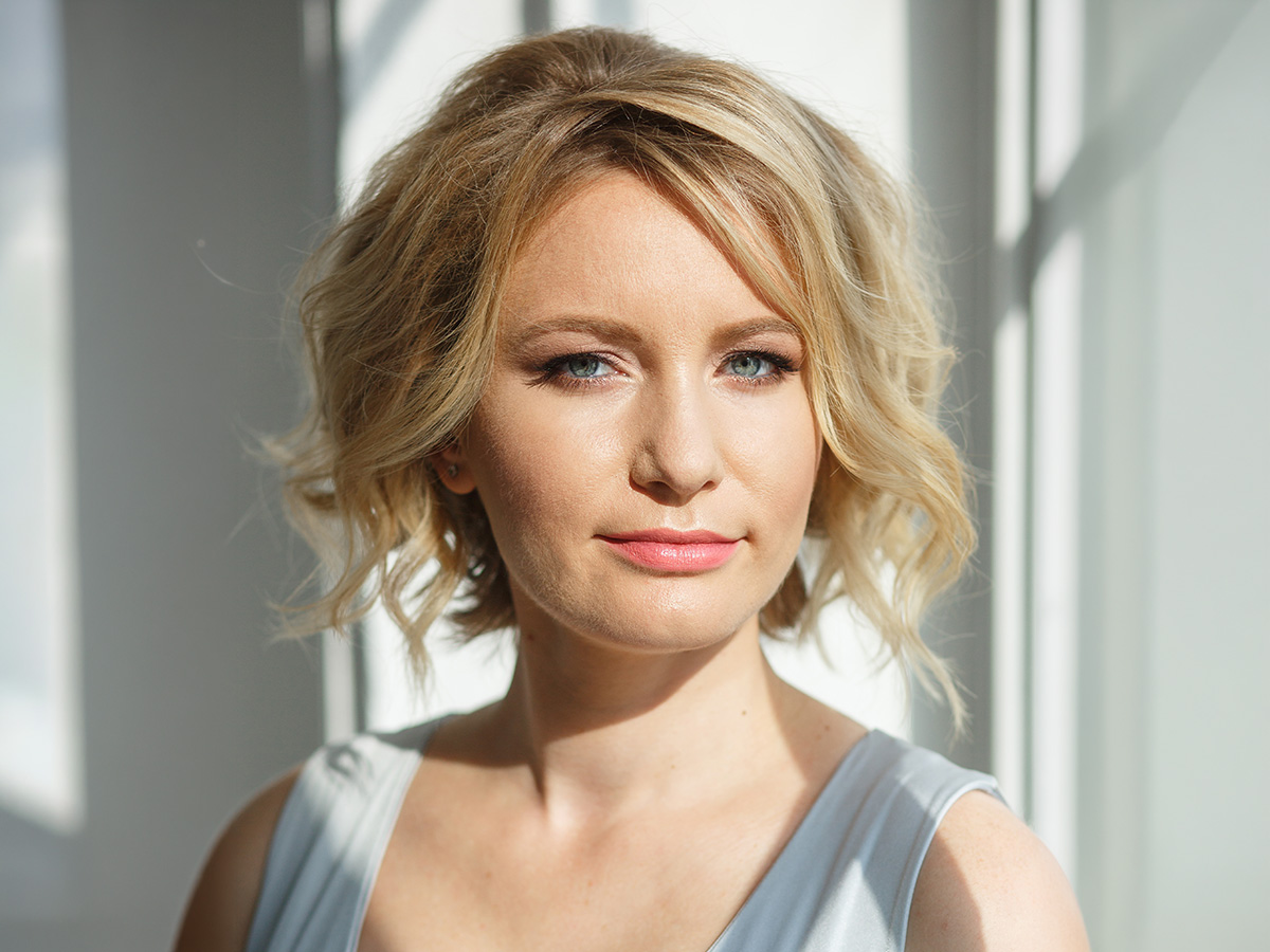 Woman with refreshed appearance and smoother eyelids after blepharoplasty in a softly lit indoor setting