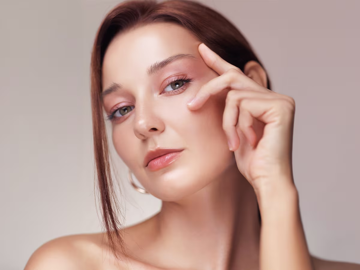 Woman gently touching under-eye area highlighting smoother skin and improved eyelid appearance after blepharoplasty