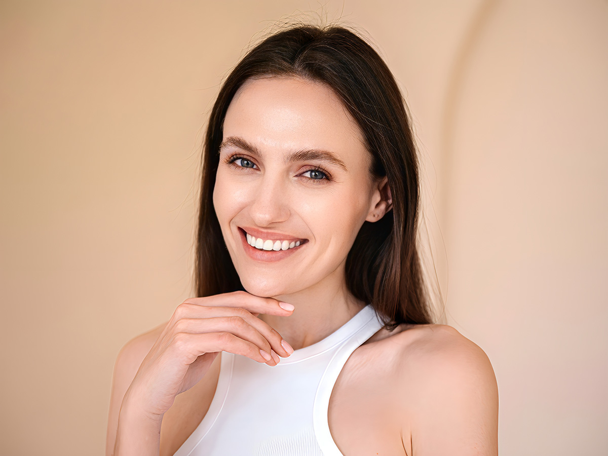 Smiling woman with smooth forehead and lifted brows representing youthful results from brow lift procedure.
