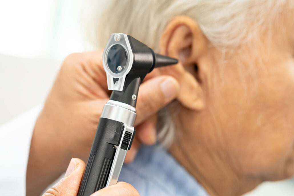 Doctor examining patient ear with otoscope to diagnose ear infection and hearing-related conditions.