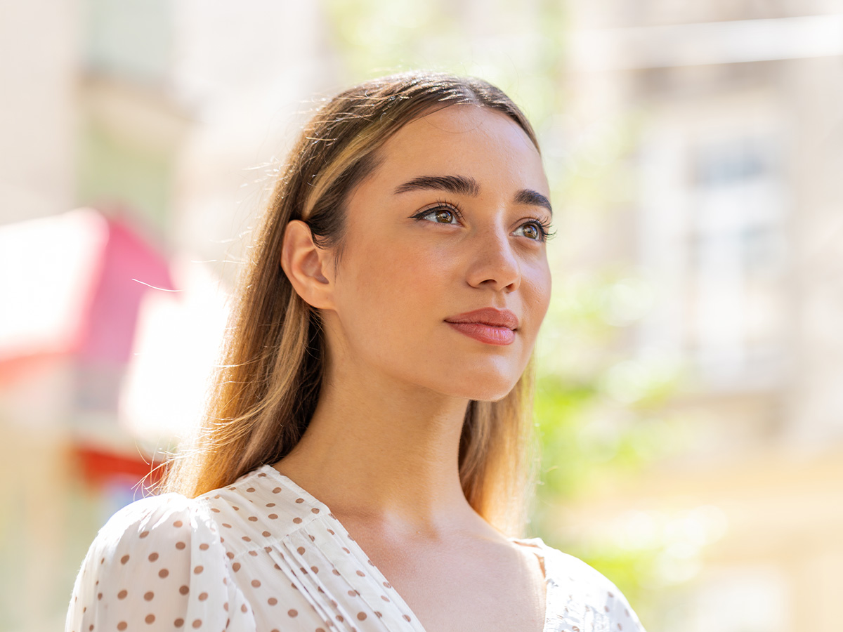 Woman with smooth, youthful skin outdoors, illustrating natural facial rejuvenation with fat grafting in New Jersey