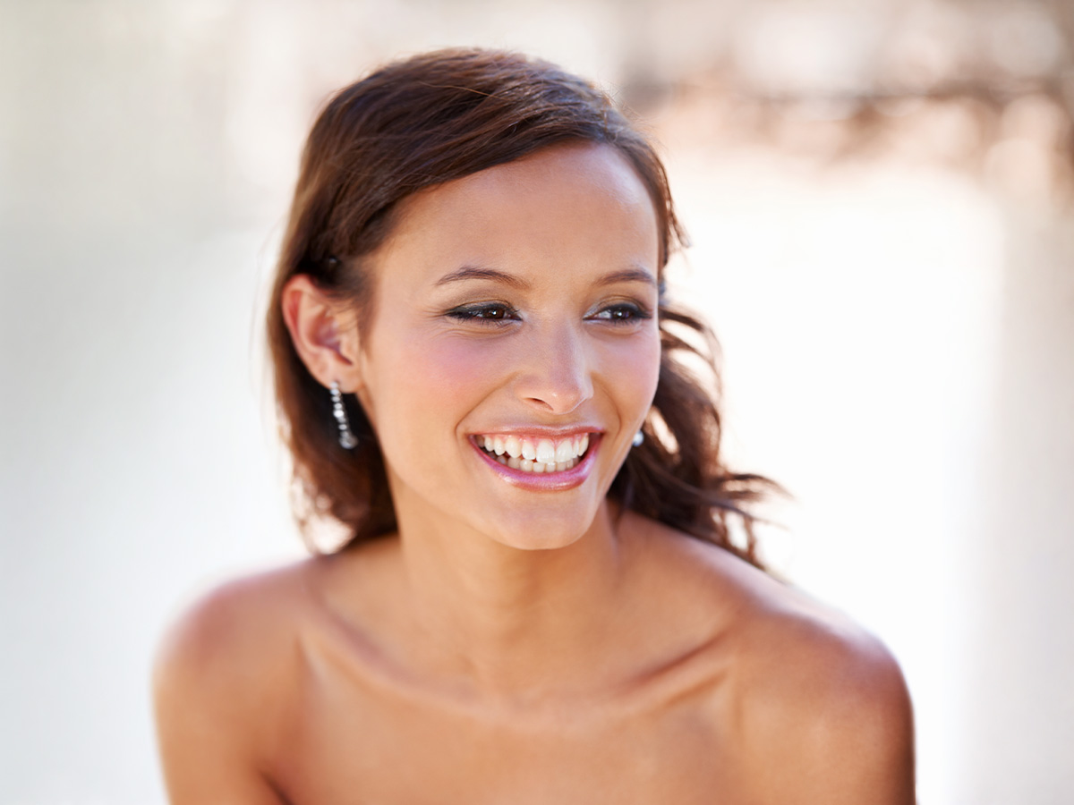 Woman with radiant skin smiling after facial treatment at New Jersey medical spa.
