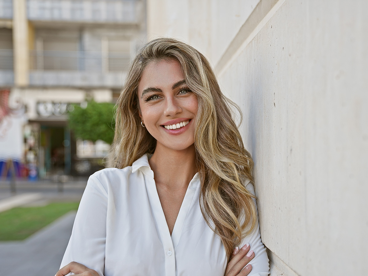 Smiling woman with clear, radiant skin outdoors, representing IPL treatment benefits in New Jersey skincare