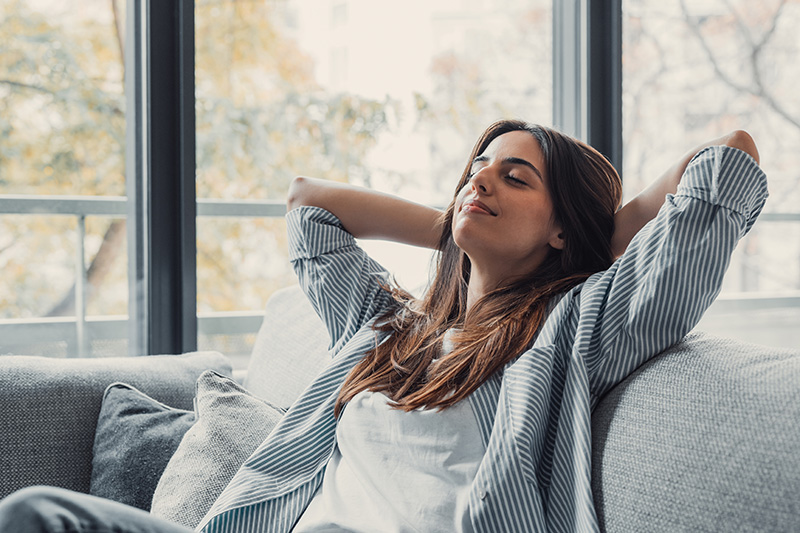 Relaxed woman sitting comfortably at home, illustrating quick recovery and no downtime after Jeuveau treatment