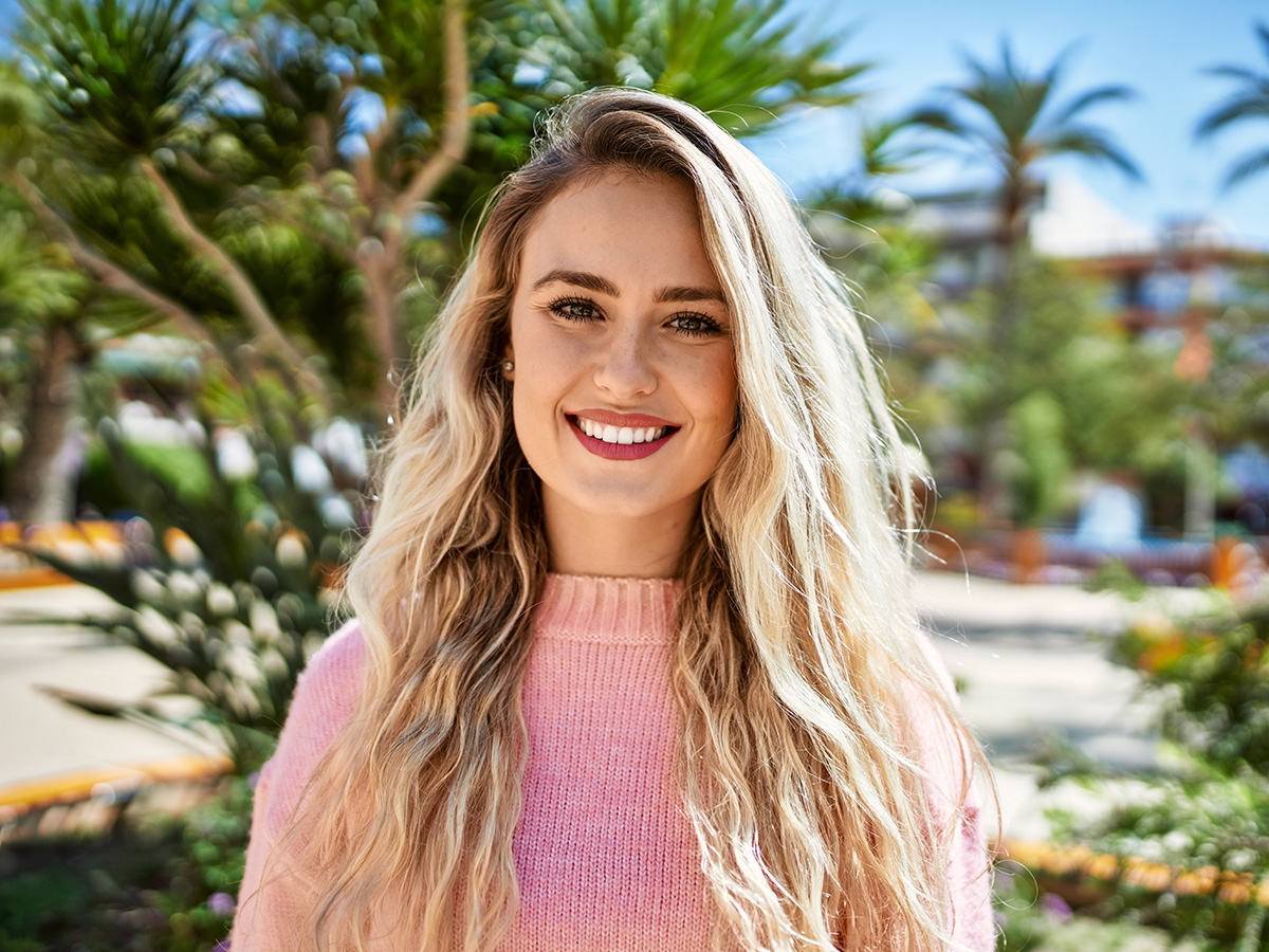 Smiling woman outdoors representing Juvederm treatment benefits for facial volume restoration and smoother skin in New Jersey.