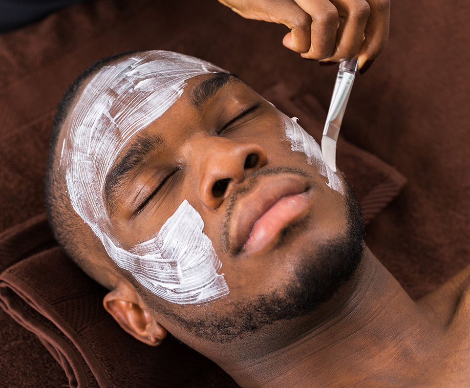 Man receiving facial treatment with cleansing mask for exfoliation and hydration at a spa