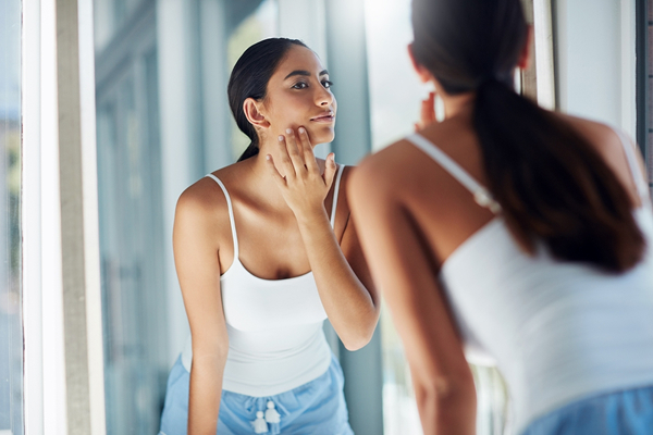 Woman examining smoother skin after microneedling treatment to improve tone, texture, and youthful appearance.