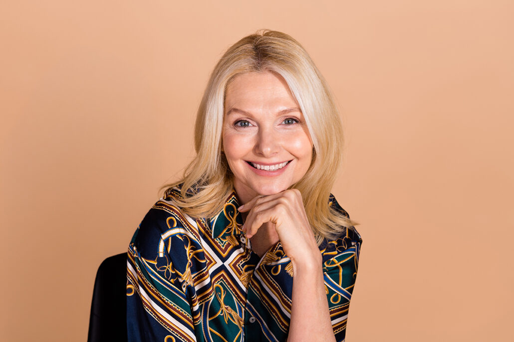 Smiling mature woman with smooth skin and defined jawline, representing natural-looking mini facelift results