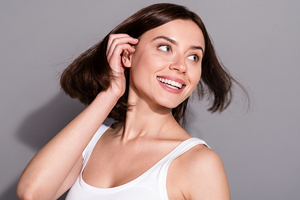 Smiling woman showing confidence after otoplasty procedure improving ear appearance