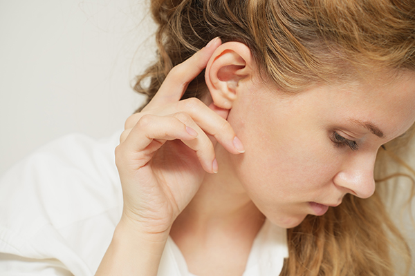 Woman touching ear after otoplasty procedure to improve ear function and overall ear structure
