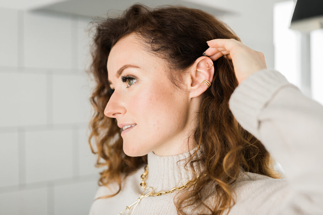Woman adjusting hair revealing natural-looking ear after otoplasty procedure in New Jersey
