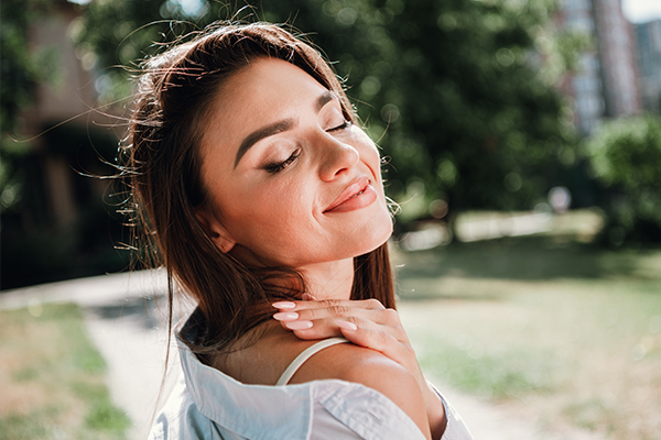 Woman smiling confidently outdoors after scar treatment improving skin appearance and self-esteem
