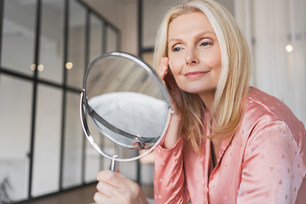 Woman examining skin in mirror after scar treatment improving mobility and reducing contracture effects
