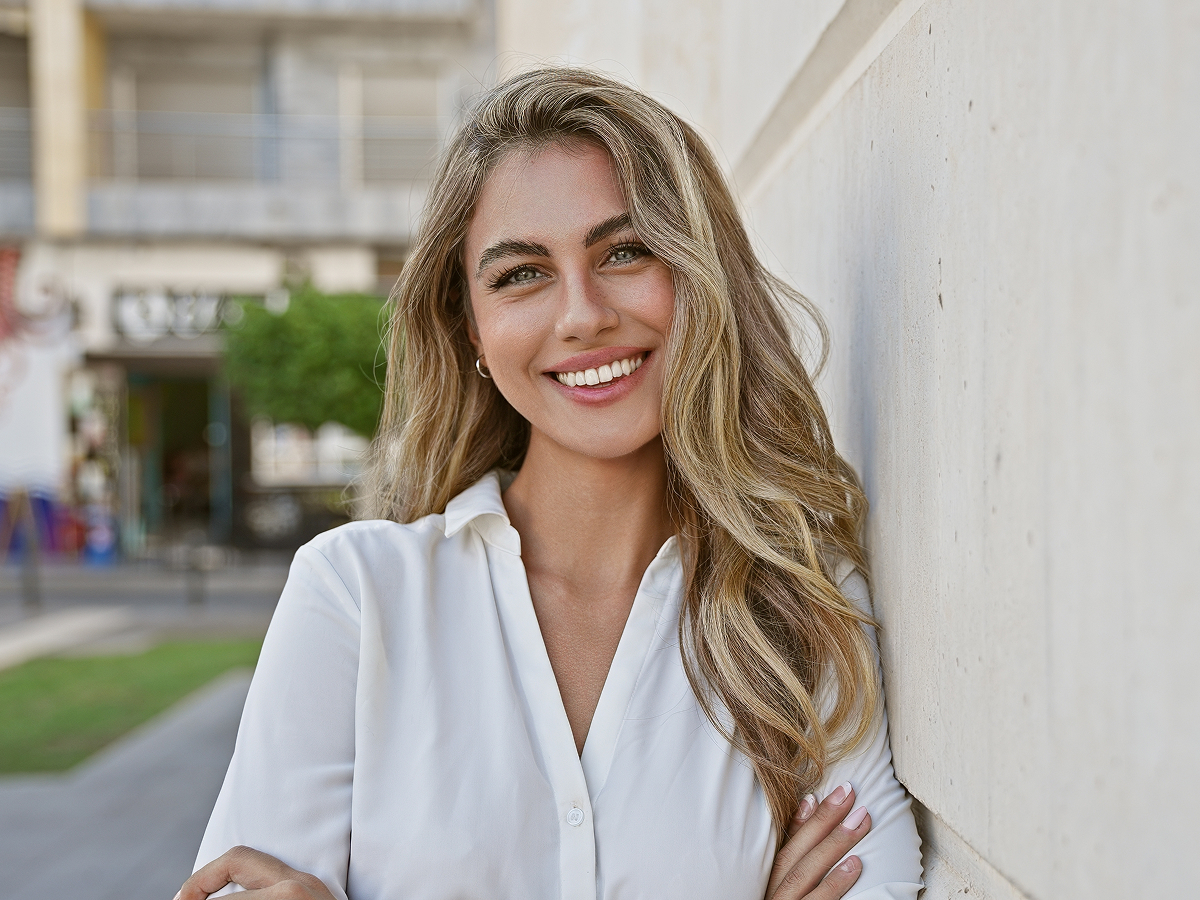 Smiling woman outdoors representing Voluma treatment benefits for fuller cheeks, smoother skin, and defined jawline in New Jersey