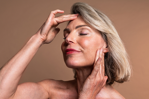 Mature woman touching her face beside deep plane facelift text about natural tissue repositioning.