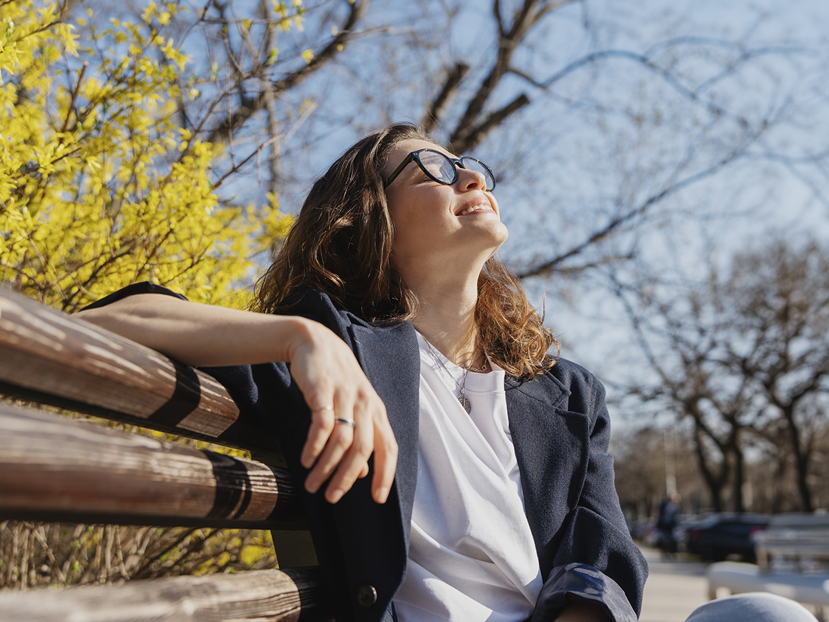Woman relaxing outdoors representing facelift surgery for structural facial aging, skin laxity, and jawline changes.