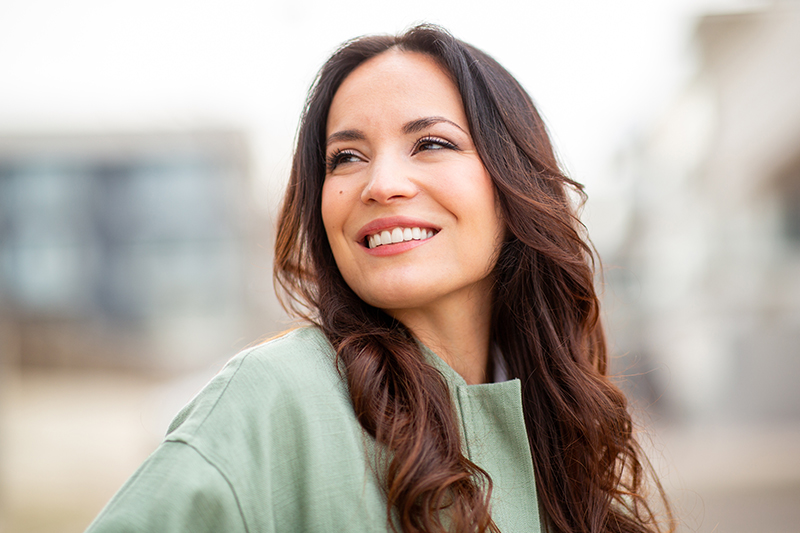 Smiling woman representing mini facelift surgery for subtle refinement and early signs of facial aging.