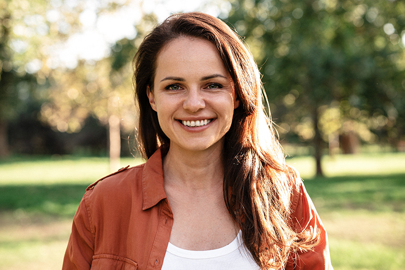 Smiling woman outdoors representing primary and revision rhinoplasty planning for natural nasal refinement