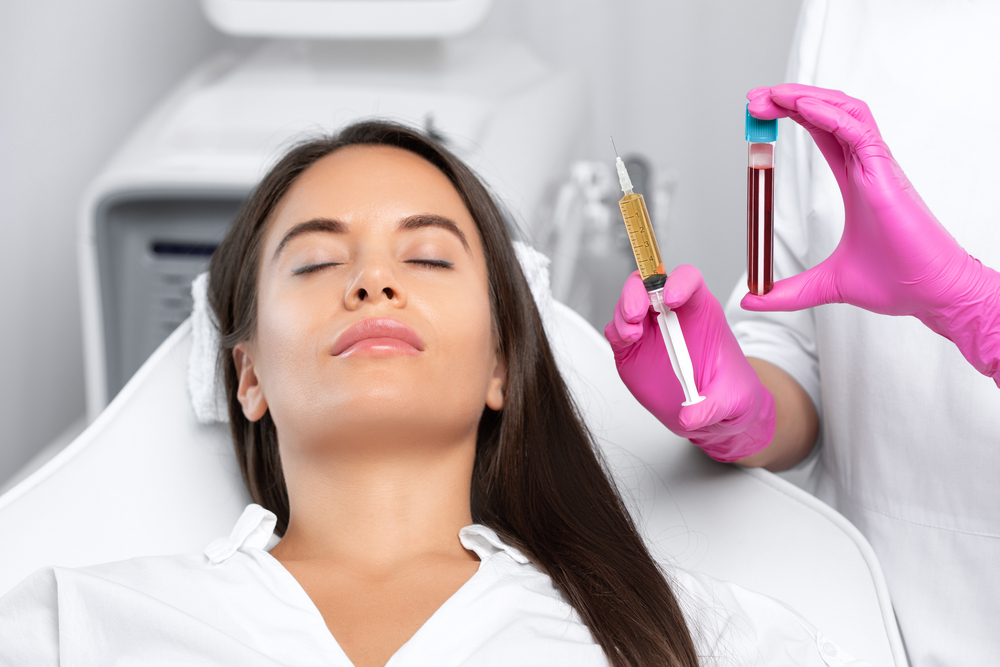 Woman preparing for PRP treatment with syringe and blood vial for skin rejuvenation.