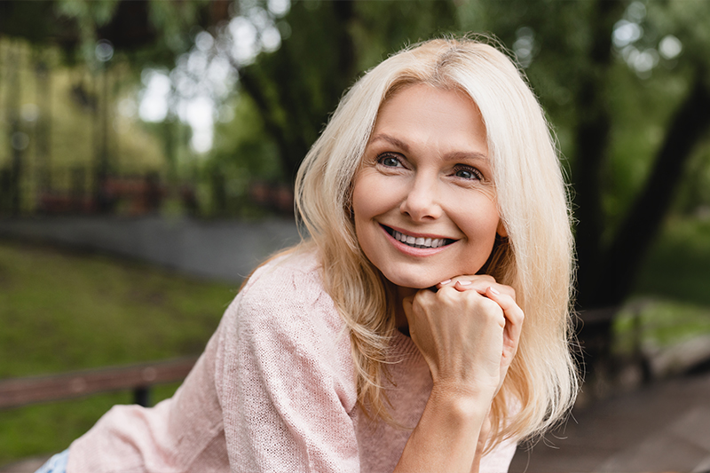 Smiling mature woman representing traditional facelift surgery for jawline smoothing and reduced sagging skin