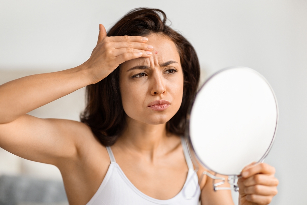 Woman checking forehead in mirror beside PRP and nanofat scar treatment options for surgical and standalone healing.