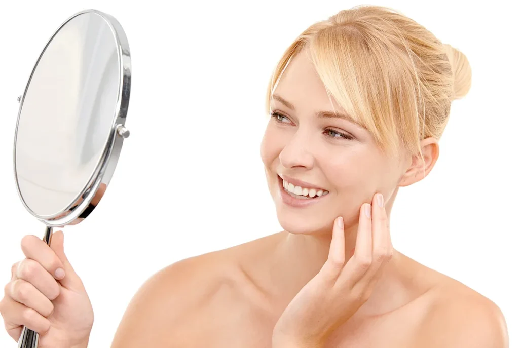 Woman examining smooth facial skin in a handheld mirror.